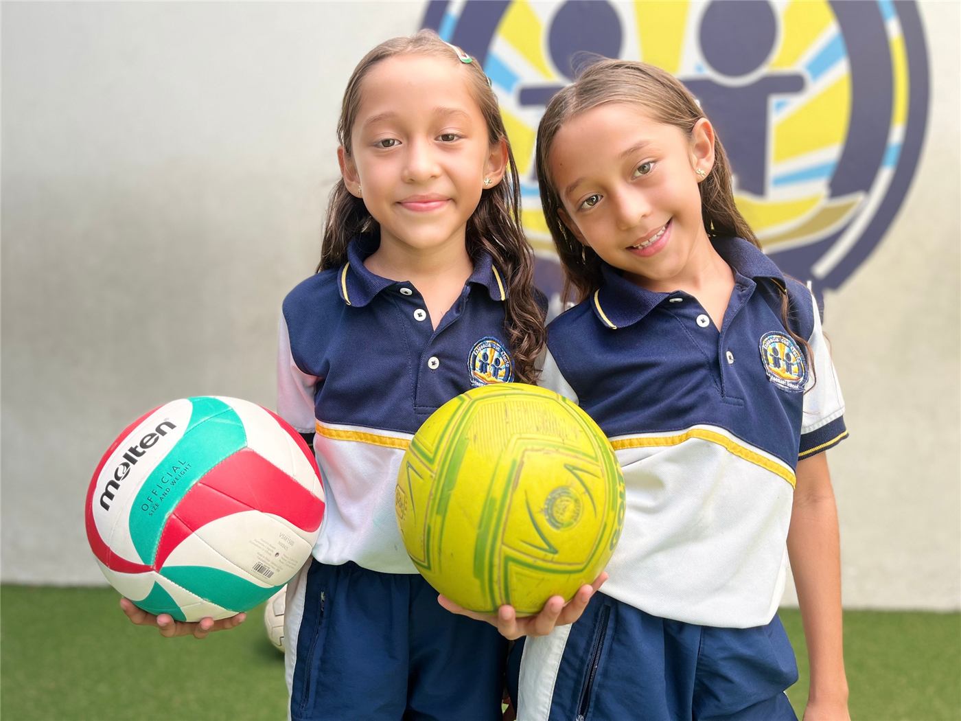 Dos estudiantes de Getsemaní con uniforme y balones de voleibol